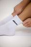 Person wearing white socks with a brand logo on a light background