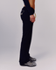 A side-profile studio shot of a model wearing dark navy blue pants with a yellow graphic detail on the back pocket, against a light gray background.