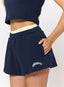 Closeup of woman wearing navy waffle baby tee and shorts with 'des vu' branding on a white background.