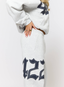 Closeup of woman wearing grey joggers with navy '422' branding on a white background.
