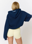 Woman wearing navy hoodie on a white background.