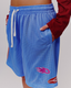 A woman modeling blue icon mesh shorts with icon badges, against a white studio background.