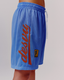 A woman modeling blue icon mesh shorts with a large orange 'dès vu' logo, against a white studio background.