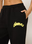 Closeup of woman wearing black waffle joggers with citron 'desvu' branding on a white background.