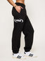 Black cuffed joggers with DÈS VU logo  on a plain background
