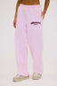 Person wearing a pink joggers with burgundy dés vu logo on a white background