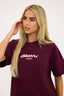 Woman wearing a burgundy t-shirt with 'dèsvu' logo on a white background