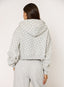 Person wearing a light gray hoodie with black polka dots and matching pants on a white background