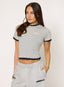 Woman wearing a gray crop top and sweatpants with 'devu' branding on a plain background