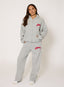 Woman wearing grey waffle hoodie and joggers with coral 'desvu' branding on a white background.