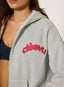 Closeup of a woman wearing unzipped grey waffle hoodie with coral 'desvu' branding on a white background.