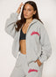Woman wearing unzipped grey waffle hoodie with coral 'desvu' branding on a white background.