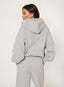 Woman wearing grey waffle hoodie on a white background.