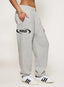 Grey cuffed joggers with DÈS VU logo  on a plain background