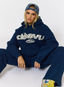 Woman wearing navy tracksuit with leopard print pattern 'des vu' branding on a white background.