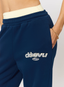 Closeup of navy joggers with leopard print pattern 'des vu' branding on a white background.