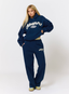 Woman wearing navy tracksuit with leopard print pattern 'des vu' branding on a white background.