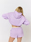Woman wearing lilac hoodie with 'des vu' branding on a white background.
