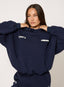 Person wearing a navy tracksuit with visible branding on a plain background