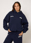 Person wearing a navy tracksuit with visible branding on a plain background
