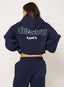 Person wearing a navy blue tracksuit with 'desvu' branding on the back against a white background