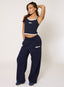 Woman wearing navy blue tank top and sweatpants with brand logo on a white background