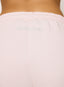 Woman wearing light pink joggers with 'des vu' branding on a white background.