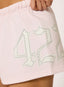 Closeup of light pink shorts with studded '422' logo on a white background.