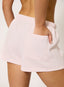 Woman wearing light pink shorts on a white background.