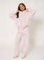 Woman wearing light pink zip up hoodie and tracksuit with studded '422' logo on a white background.