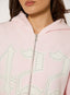 Closeup of light pink zip up hoodie with studded '422' logo on a white background.