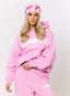 Woman wearing pink hoodie with 'des vu' branding on a white background.