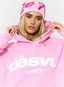 Closeup of woman wearing pink hoodie with 'des vu' branding on a white background.
