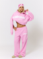 Woman wearing pink tracksuit with 'des vu' branding on a white background.