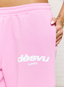Closeup of pink joggers with 'des vu' branding on a white background.