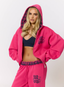Woman wearing pink hoodie with teddy plaid print 'des vu' branding on a white background.