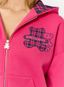 Closeup of woman wearing pink hoodie with teddy plaid print 'des vu' branding on a white background.