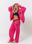 Woman wearing pink hoodie with teddy plaid print 'des vu' branding on a white background.