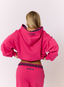 Woman wearing pink hoodie on a white background.
