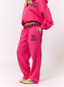 Woman wearing pink joggers with teddy plaid print 'des vu' branding on a white background.