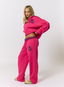 Woman wearing pink tracksuit with teddy plaid print 'des vu' branding on a white background.