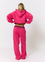 Woman wearing pink joggers with teddy plaid print 'des vu' branding on a white background.
