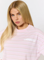 Closeup of woman wearing pink striped t shirt with 'des vu' branding on a white background.