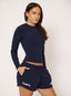 Woman wearing navy blue long-sleeve top and shorts with 'desvu' branding on a light background