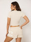Woman wearing stone t-shirt and shorts on a white background.