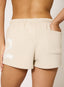 Closeup of woman wearing stone shorts on a white background.