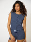 Woman wearing a navy and white striped sleeveless top and shorts on a plain background