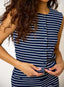 Person wearing a navy and white striped dress with a plain background
