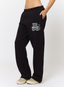 Woman wearing black joggers with teddy plaid print 'des vu' branding on a white background.