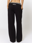Woman wearing black joggers 'des vu' branding on a white background.